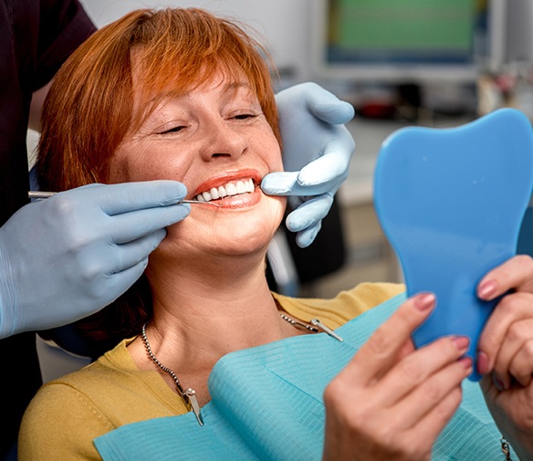 Woman looking at smile during preventive dentistry checkup
